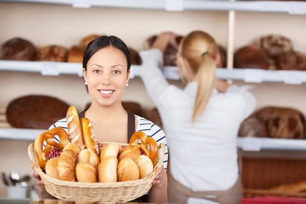 Frau in Bäckerei zeigt Brotlaibe im Korb — Stockfoto