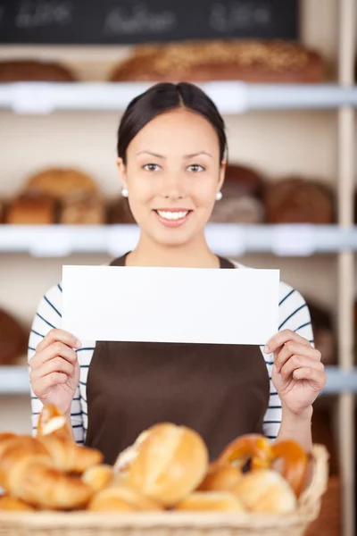 Young woman at bakery counter displaying paper — Stock Photo, Image