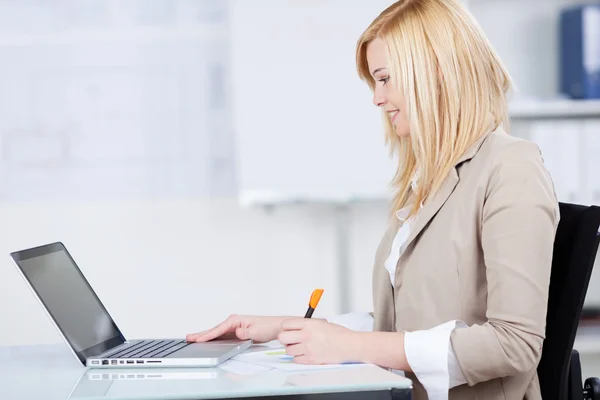 Geschäftsfrau zeichnet Balkendiagramm, während sie auf Laptop schaut — Stockfoto