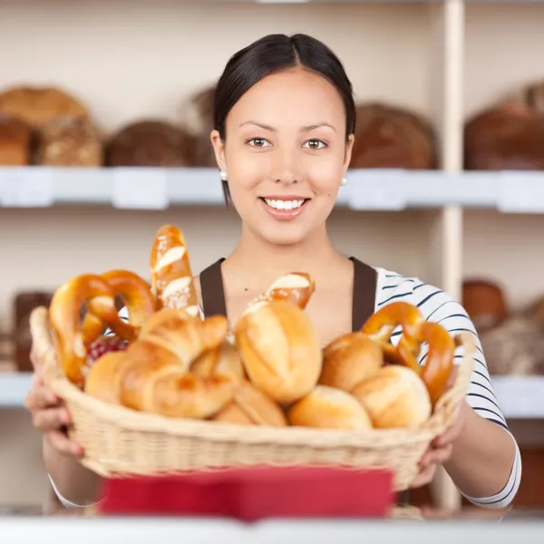 Lächelnde Verkäuferin hält Brotkorb in Bäckerei — Stockfoto