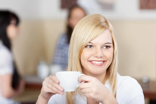 Fröhliche junge Frau trinkt Kaffee im Café — Stockfoto