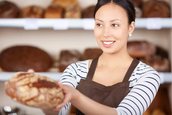 Mulher passando pão ao balcão na padaria — Fotografia de Stock