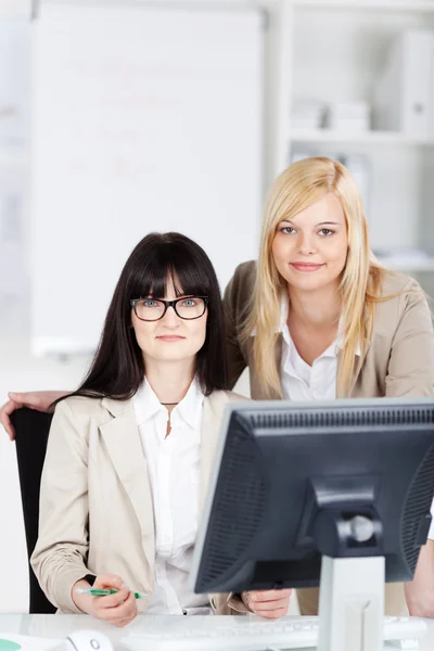 Dos jóvenes empresarias sentadas en el escritorio — Foto de Stock