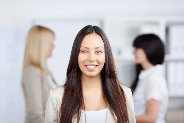 Empresária sorrindo com colegas de trabalho do sexo feminino no fundo Imagem De Stock