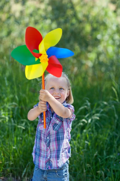 Klein meisje met een regenboog gekleurde windmolen — Stockfoto