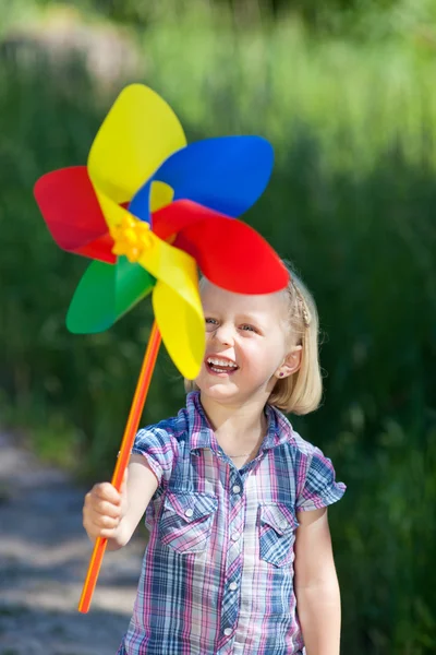 Smiling little girl with a colourful pinwheel — Stock Photo, Image