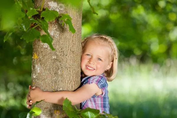 Niña feliz abrazando un árbol — Foto de Stock