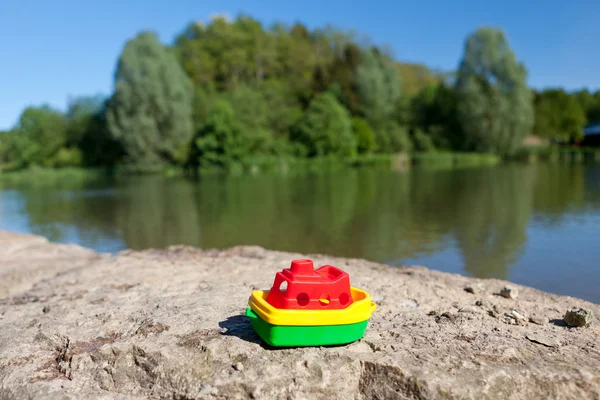 Маленький барвистий пластиковий човен біля озера — стокове фото