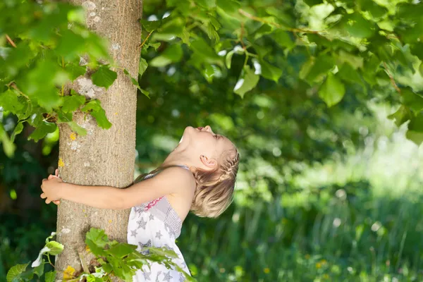 Jong meisje knuffelen een boomstam — Stockfoto