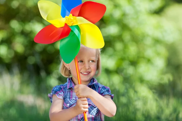 Cute young girl with a colourful windmill — Stock Photo, Image