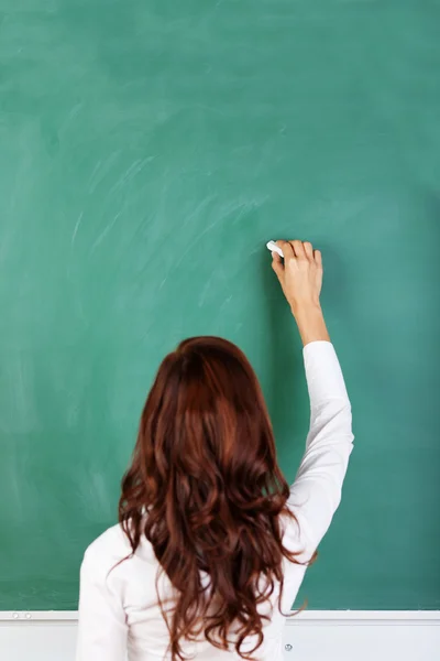 Student or teacher writing on a blackboard — Stock Photo, Image