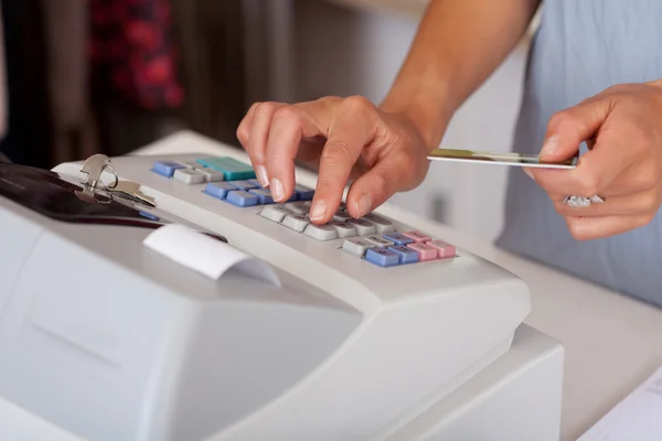Verkoopster creditcard houden tijdens het gebruik van de kassa — Stockfoto