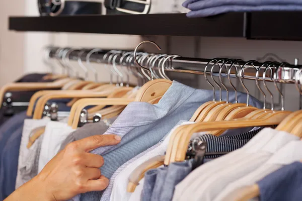 Frauenhand wählt Hemd aus Kleiderständer im Bekleidungsgeschäft — Stockfoto