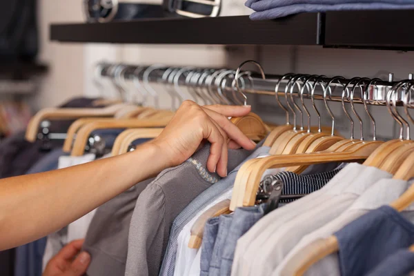 Kvinnans hand välja skjorta från rack — Stockfoto