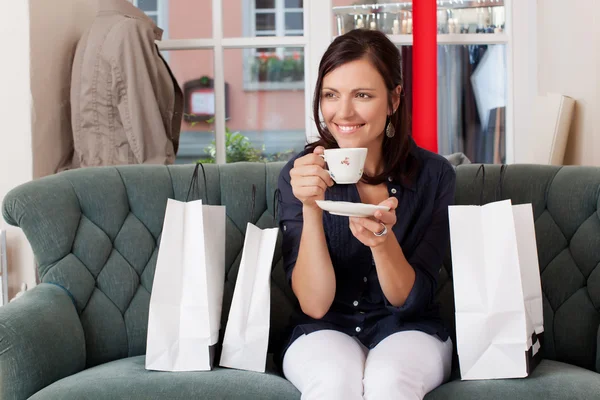 Cliente che beve caffè mentre si siede sul divano al negozio di abbigliamento — Foto Stock