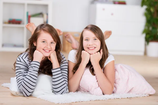 Twee mooie jonge tienermeisjes die tot op de vloer — Stockfoto