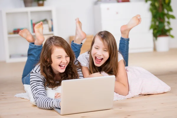 Two young teenage girls using a laptop laughing — Stock Photo, Image
