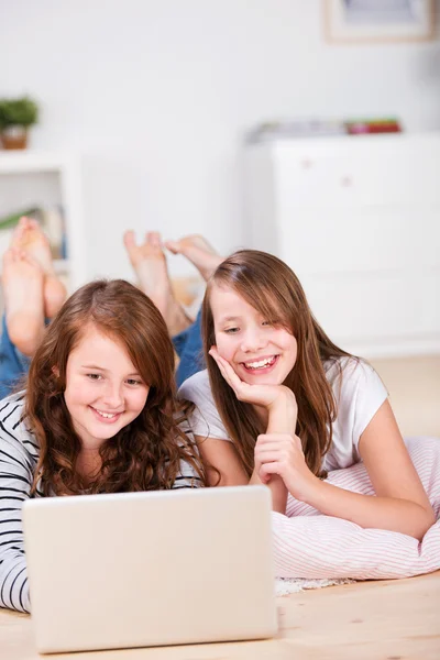 Two amused young teenage girls using a laptop — Stock Photo, Image