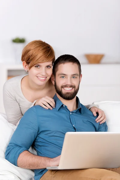 Feliz pareja joven con ordenador portátil — Foto de Stock