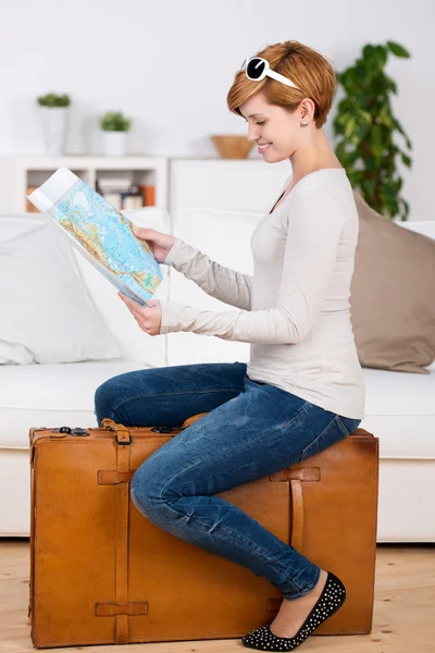 Woman Looking At Map While Sitting On Suitcase — Zdjęcie stockowe