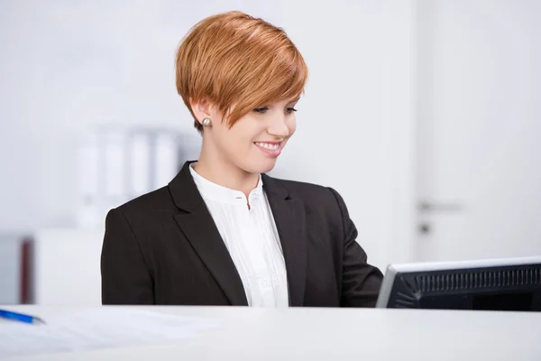 Recepcionista olhando para o computador — Fotografia de Stock