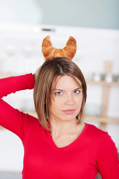 Mulher brincalhão segurando um croissant como chifres — Fotografia de Stock