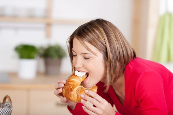 Frau beißt in eine frische, flockige Coissant — Stockfoto