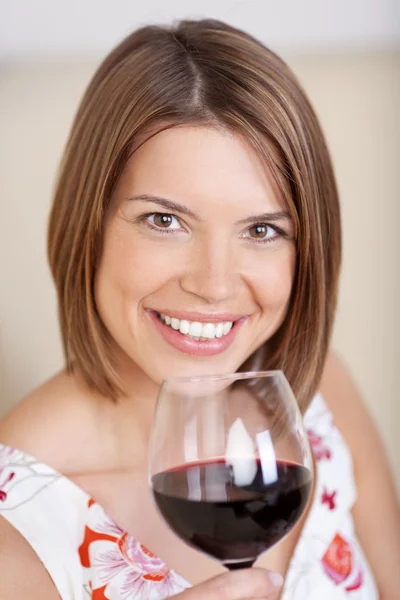 Mulher sorridente com um copo de vinho tinto — Fotografia de Stock