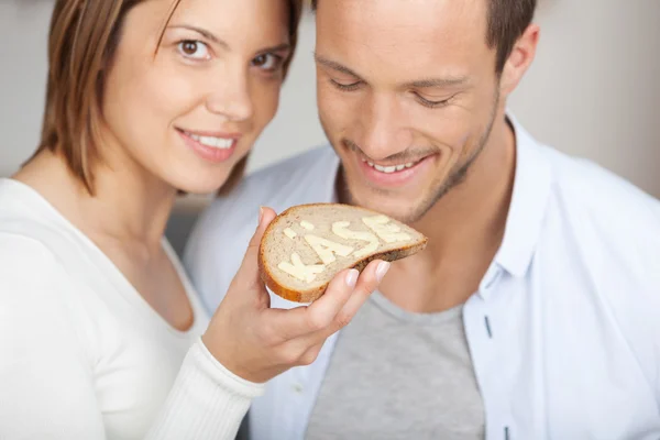 Casal sorridente segurando uma fatia de pão e queijo — Fotografia de Stock