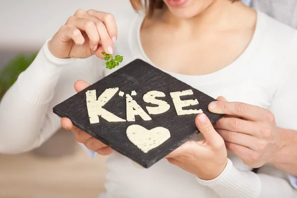 Mujer joven sosteniendo una losa de piedra con queso — Foto de Stock