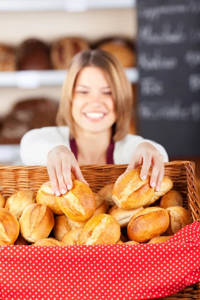 Friendly bakery worker selecting rolls — Stock Photo, Image