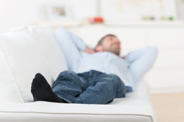 Man With Hands Behind Head Lying On Couch clipart
