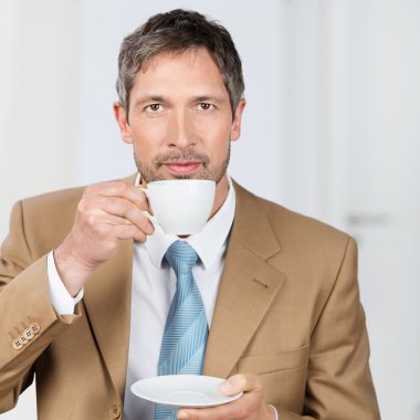 Businessman Enjoying Coffee In Office clipart