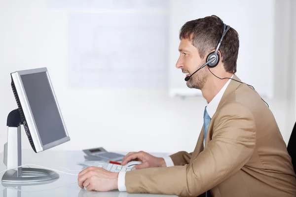 Lachende zakenman met headset computerscherm kijken — Stockfoto