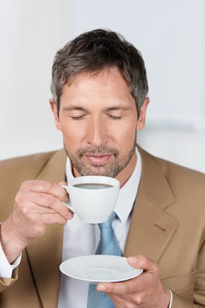 Empresário com olhos fechados desfrutando de café no escritório — Fotografia de Stock