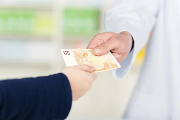 Mano del cliente que pasa el dinero al farmacéutico masculino en farmacia —  Fotos de Stock