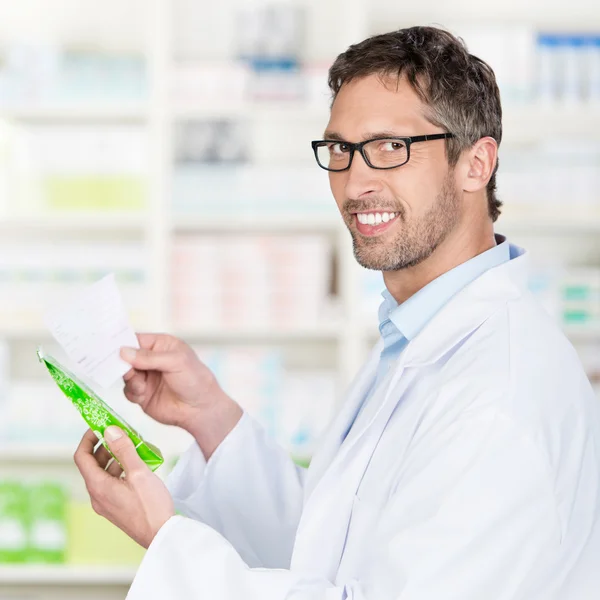 Фармацевт держит рецептурную бумагу и продукт в аптеке — стоковое фото