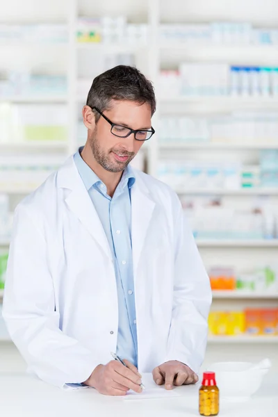 Pharmacien écrivant la prescription sur papier au comptoir de pharmacie — Photo