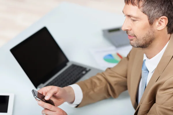 Zakenman met behulp van mobiele telefoon op balie in kantoor — Stockfoto