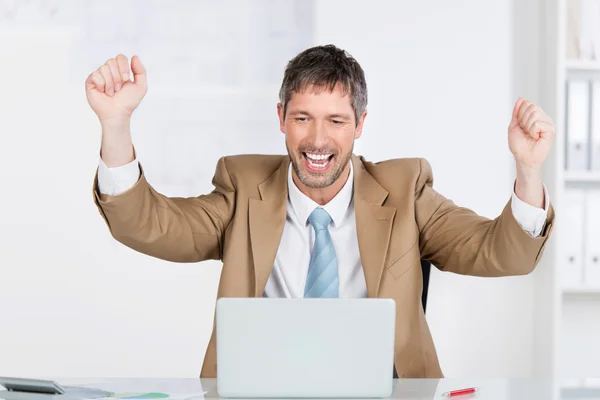 Geschäftsmann mit geballten Fäusten feiert Sieg am Schreibtisch — Stockfoto