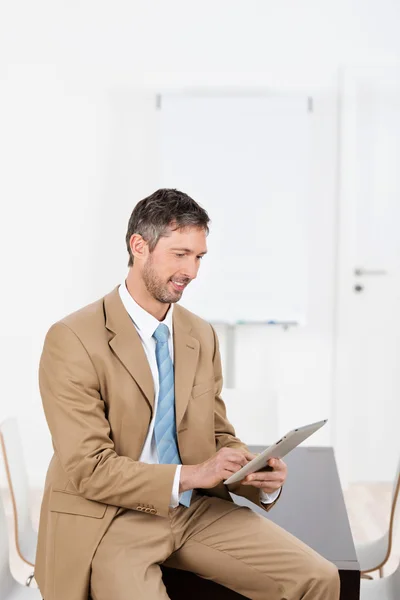 Empresário usando tablet digital enquanto sentado na mesa — Fotografia de Stock