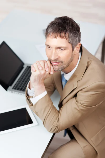 Pensativo hombre de negocios con computadora portátil y tableta digital en el escritorio —  Fotos de Stock