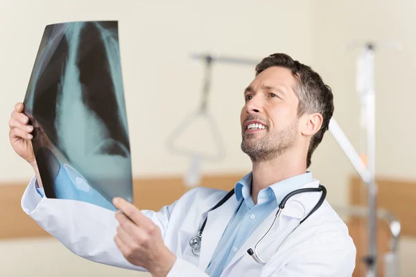 Volwassen arts kijken naar x-ray verslag in het ziekenhuis — Stockfoto