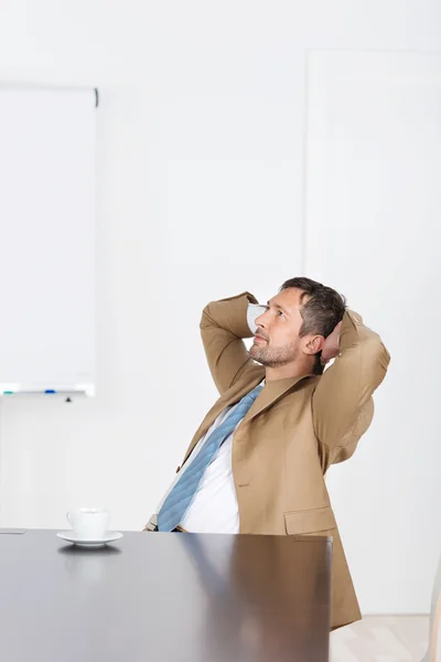 Empresario con las manos detrás de la cabeza mirando hacia el escritorio —  Fotos de Stock