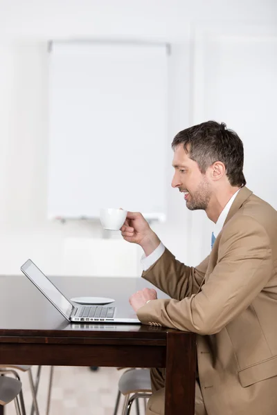 Empresario con computadora portátil y taza de café en el escritorio —  Fotos de Stock