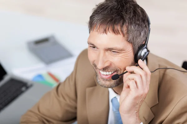 Ejecutivo de servicio al cliente conversando en auriculares en el escritorio —  Fotos de Stock