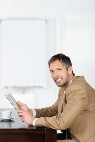 Affärsman med TabletPC när du sitter på skrivbord — Stockfoto