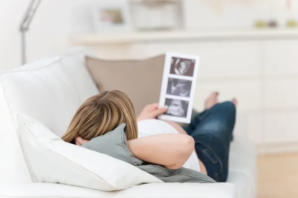 Pregnant Woman Holding Babys Ultrasound Scan On Couch — Stock Photo, Image