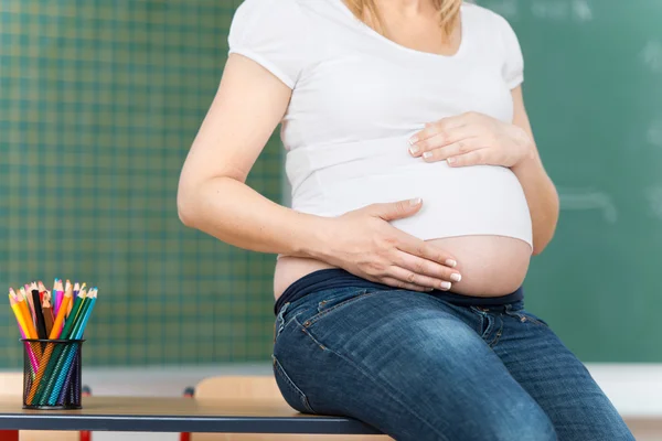 Schwangere Lehrerin mit Händen am Bauch — Stockfoto