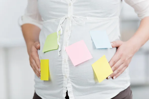 Femme d'affaires enceinte avec post-it notes coincé sur le ventre — Photo